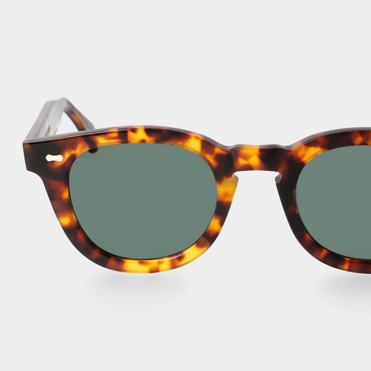 Sunglasses with tortoiseshell frame and green lenses on a white background. - DEI DUCHI