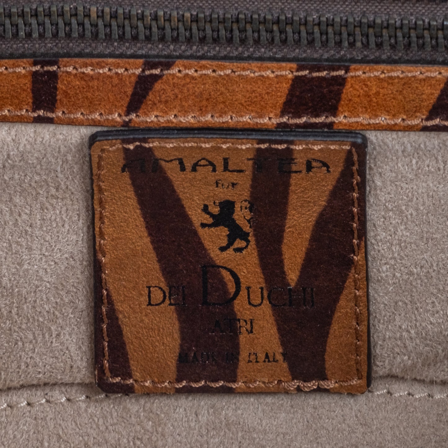 Close-up of a bag with 'Amaltea' branding and tiger pattern. -DEI DUCHI (AMALTEA)