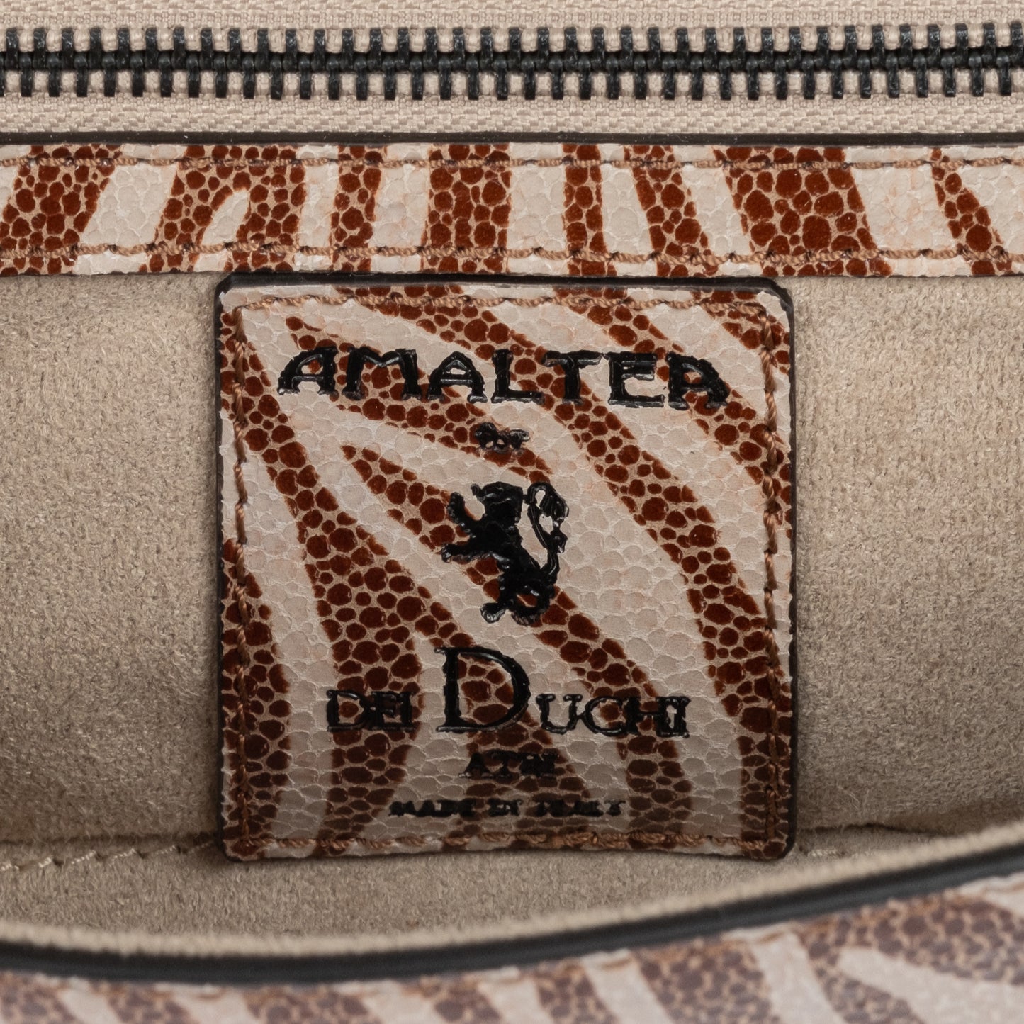 Zebra embossed pinkish leather clutch bag/wallet with a burnished metallic emblem buckle on a white background. - DEI DUCHI (AMALTEA)
