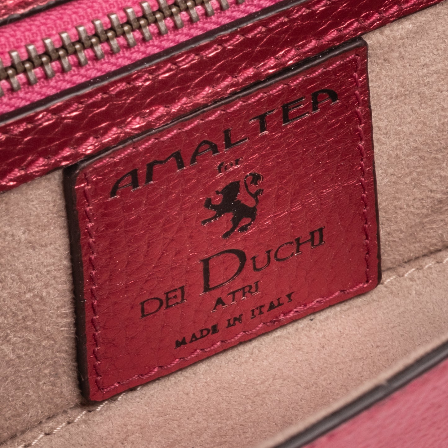 Close-up of a leather label on a handbag with 'Amaltea for  Dei Duchi' branding.