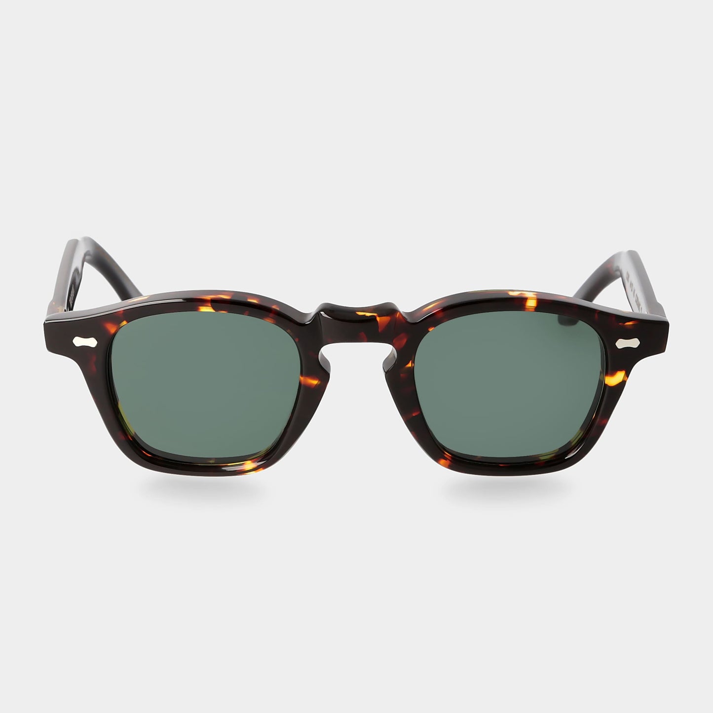Sunglasses with tortoiseshell frame and green lenses on a light gray background. - Dei Duchi