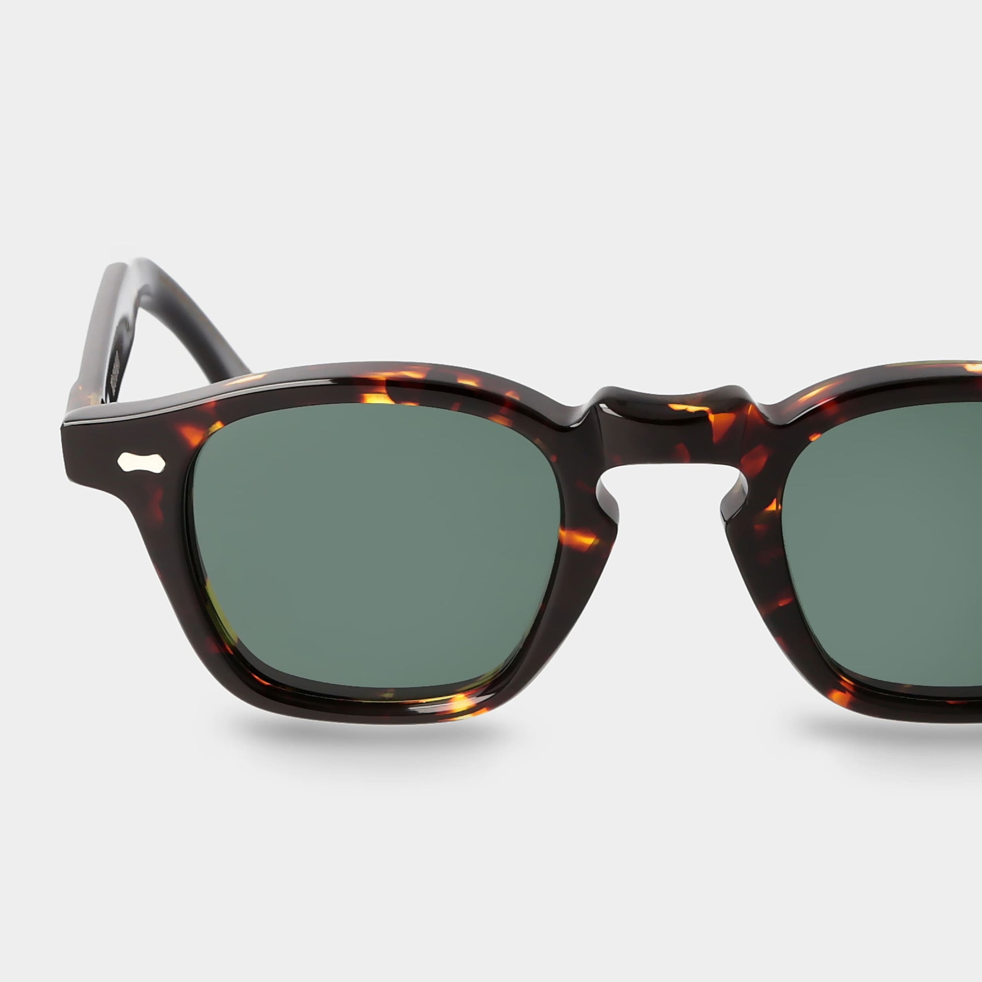 Sunglasses with tortoiseshell frame and green lenses on a light gray background. - Dei Duchi