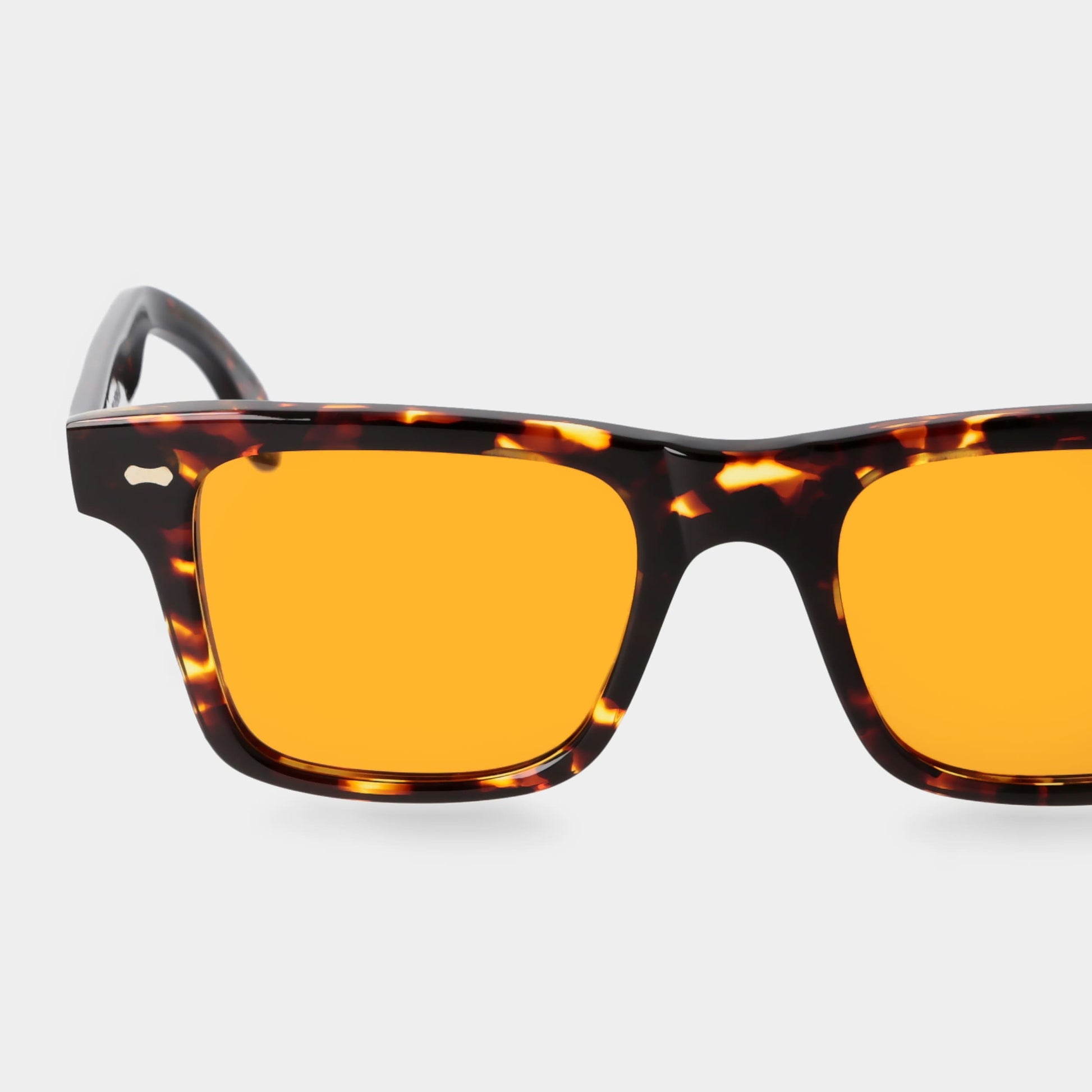 Sunglasses with tortoiseshell frame and orange lenses on a light gray background. - DEI DUCHI
