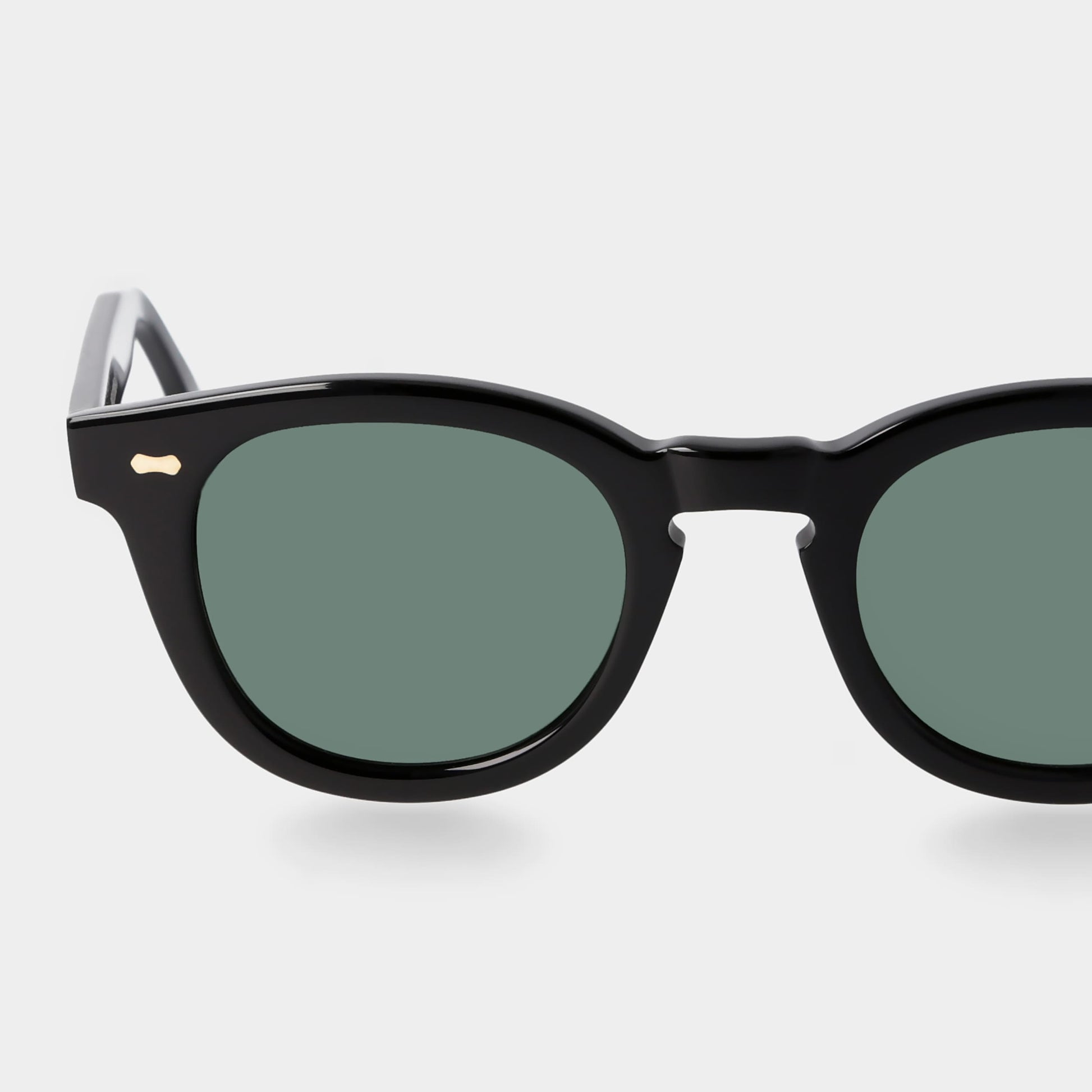 Black sunglasses with green lenses on a white background. - DEI DUCHI