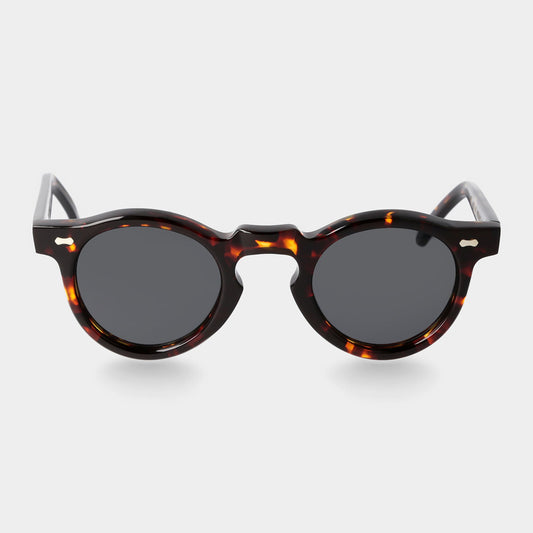 Round sunglasses with tortoiseshell frame on a light gray background. - Dei Duchi